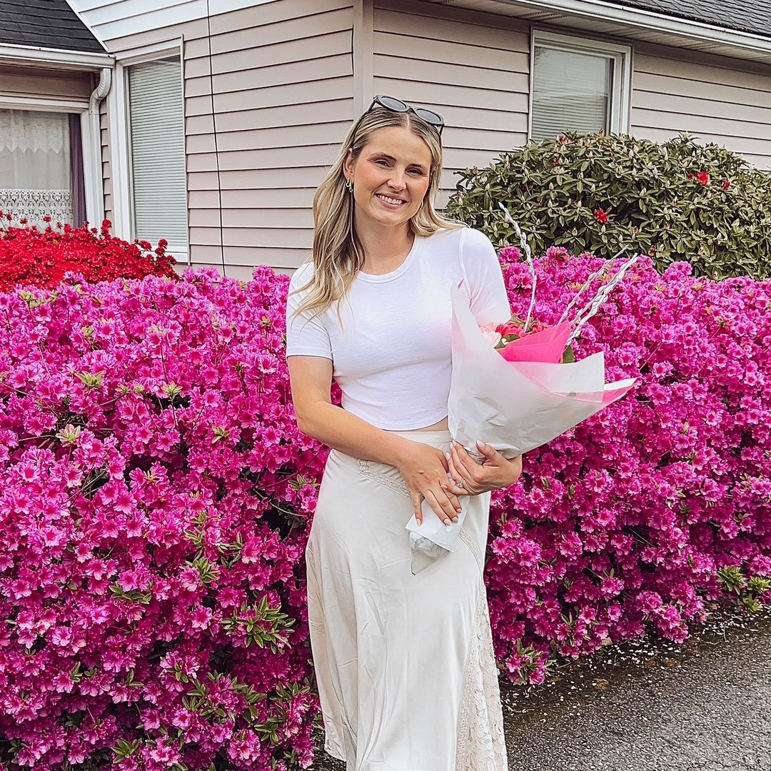woman in white in front of pink flowers