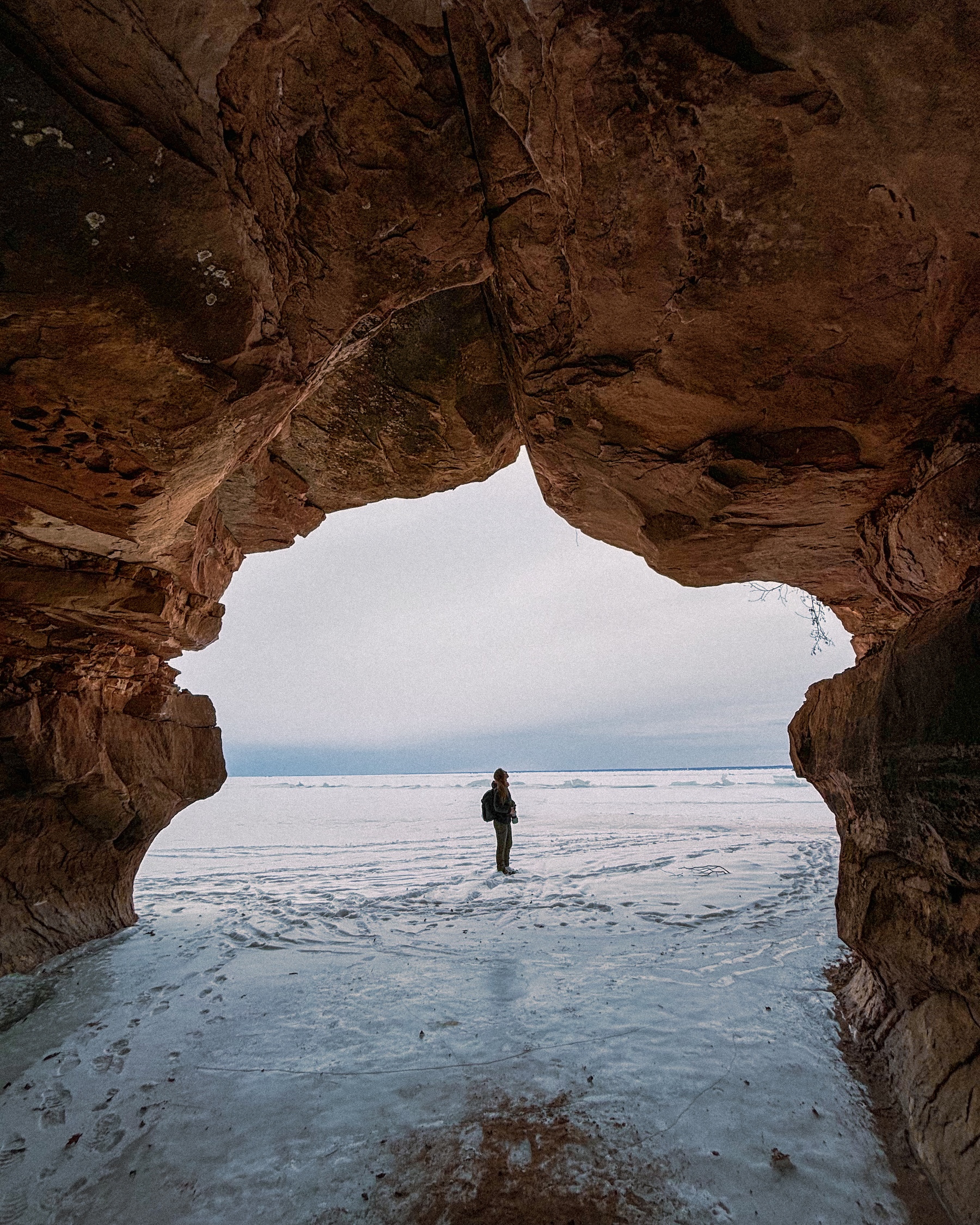 outdoor creator staring at the sky shown through the mouth of a cave
