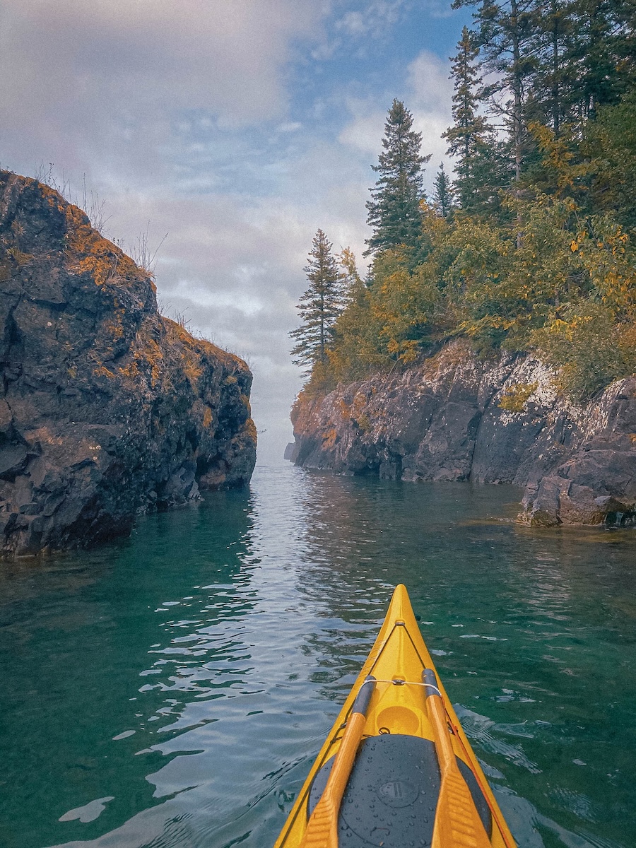 photo of a yellow kayak about to go through a beautiful narrow pass